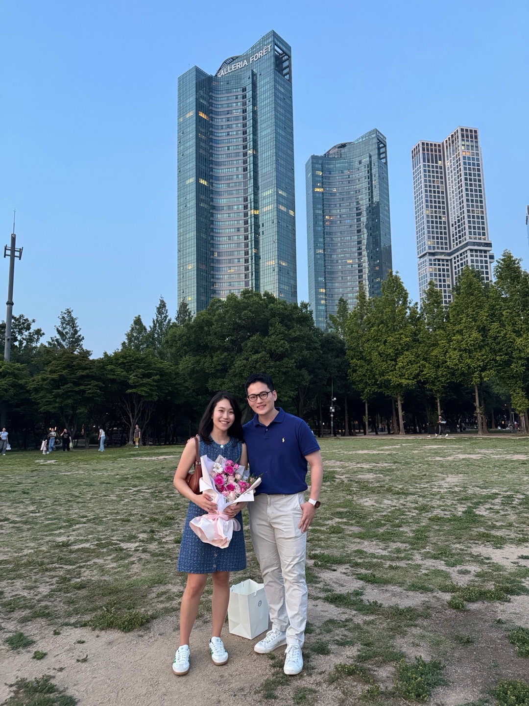 Jex and Hanna standing together in a city park holding a bouquet.